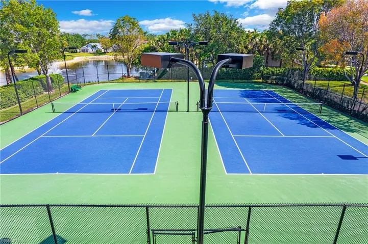 View of tennis court with a water view