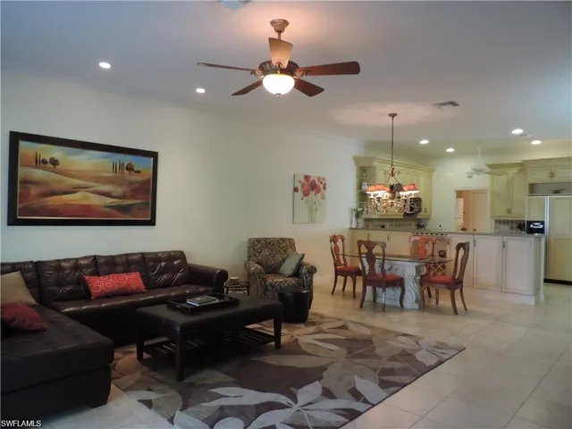 Living room featuring ceiling fan, ornamental molding, and light tile flooring
