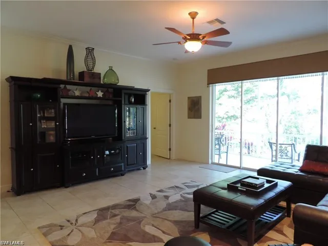 Tiled living room with ceiling fan and crown molding