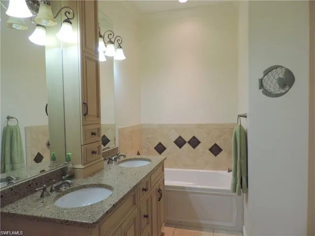 Bathroom featuring tile flooring, crown molding, double sink, a bath to relax in, and large vanity