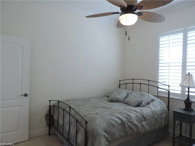 Tiled bedroom featuring ceiling fan