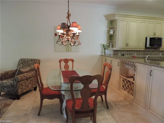 Tiled dining room with a chandelier and crown molding