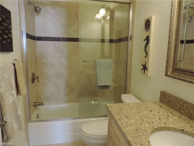 Full bathroom featuring enclosed tub / shower combo, toilet, and large vanity
