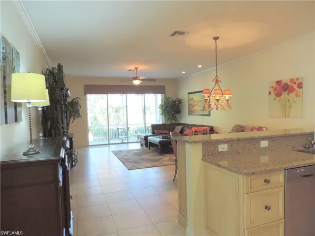 Kitchen with stainless steel dishwasher, ceiling fan with notable chandelier, light stone counters, light tile floors, and hanging light fixtures