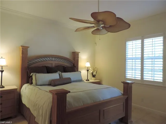Bedroom with tile floors, ceiling fan, and crown molding