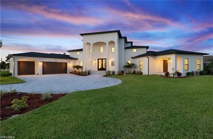 View of front facade featuring a yard, stucco siding, and decorative driveway