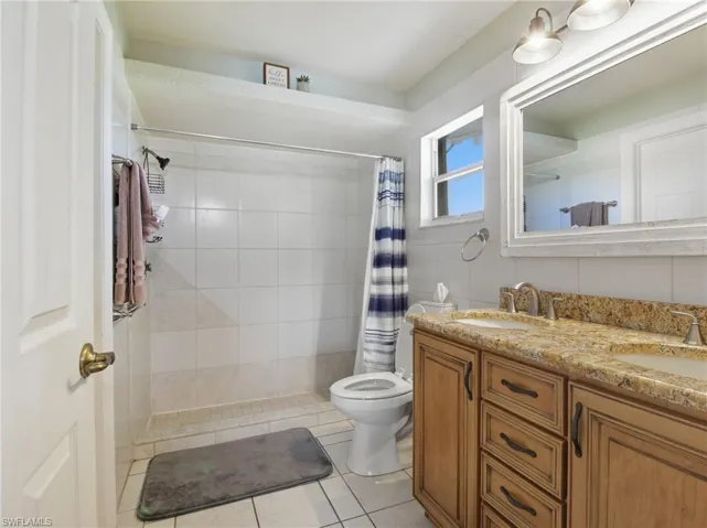 Bathroom with a shower stall, double vanity, and light tile patterned floors