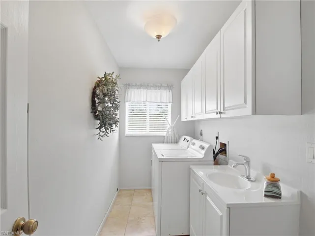 Washroom with cabinet space, separate washer and dryer, and light tile patterned flooring