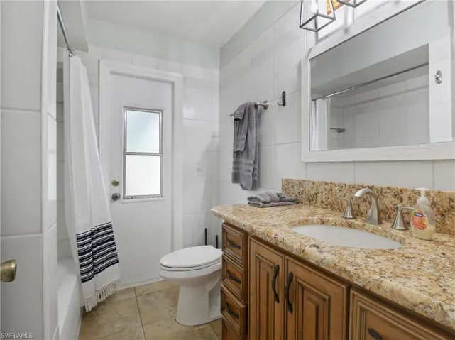 Full bathroom featuring vanity, shower / bath combo, and light tile patterned flooring