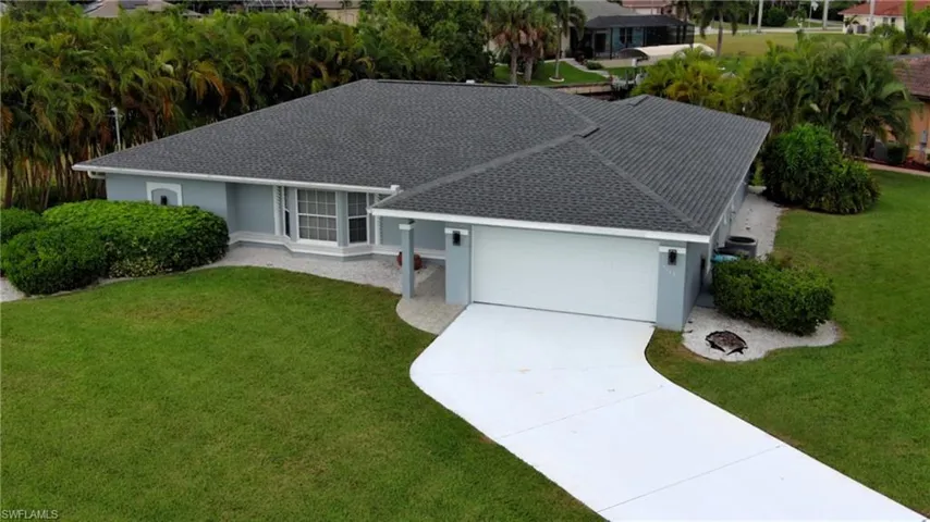 Ranch-style home with a front lawn, an attached garage, concrete driveway, and stucco siding