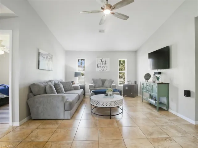 Living area with ceiling fan, lofted ceiling, and light tile patterned floors