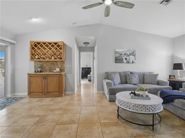 Living area with vaulted ceiling, ceiling fan, and light tile patterned floors
