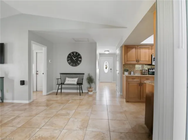 Kitchen featuring decorative backsplash, brown cabinets, light stone countertops, and light tile patterned flooring