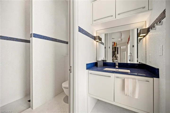 Full Bathroom accessible form the pool and outdoor area, featuring vanity, tiled shower, and light tile patterned flooring