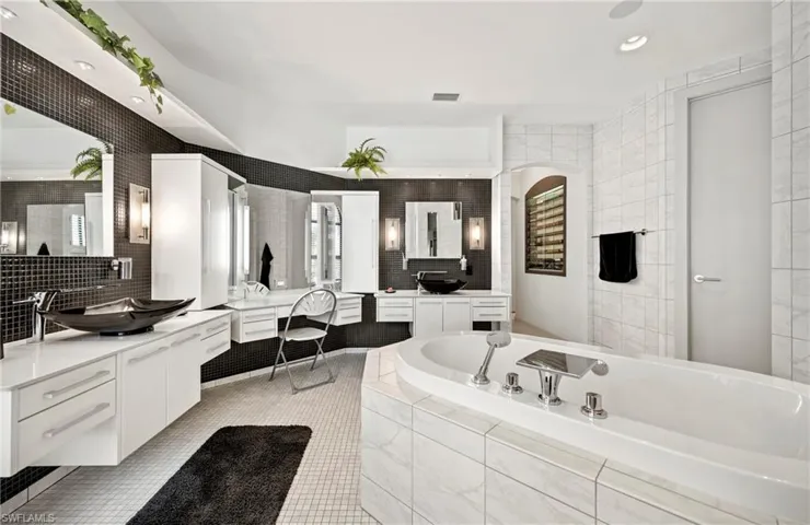 Full bath with two vanities, recessed lighting, a bath, tile walls, and decorative backsplash