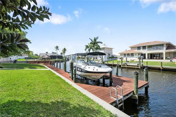 Dock with a water view, boat lift, and a yard