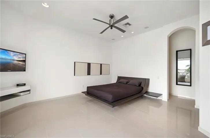 Guest Bedroom featuring light tile patterned floors, arched walkways, ceiling fan, and recessed lighting. Offering canal views and access to large balcony