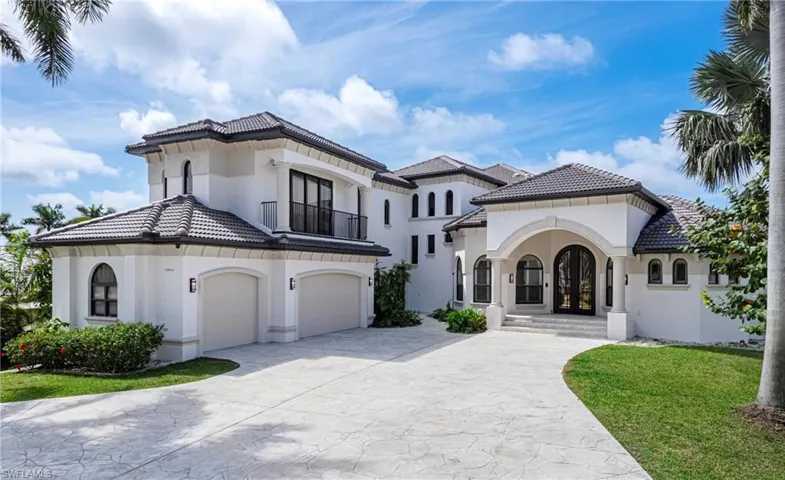 Mediterranean / spanish house with stucco siding, driveway, a balcony, a front yard, and a tiled roof