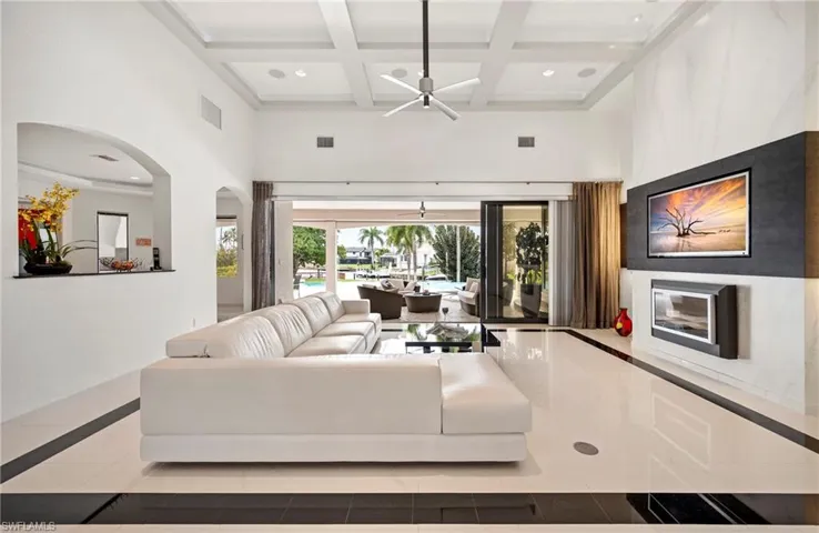 Tiled living room with inlaid floor details, coffered ceiling, recessed lighting, arched walkways, and ceiling fan