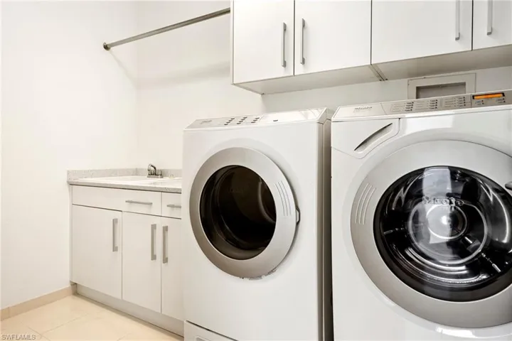 Laundry and hurricane safe room with cabinet space and separate washer and dryer