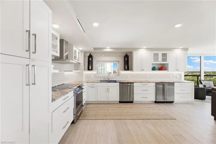 Kitchen featuring appliances with stainless steel finishes, tasteful backsplash, wall chimney exhaust hood, a sink, and recessed lighting