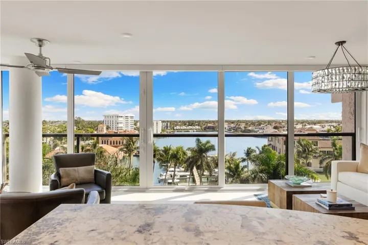 Sunroom featuring a water view, expansive windows, healthy amount of natural light, and a chandelier