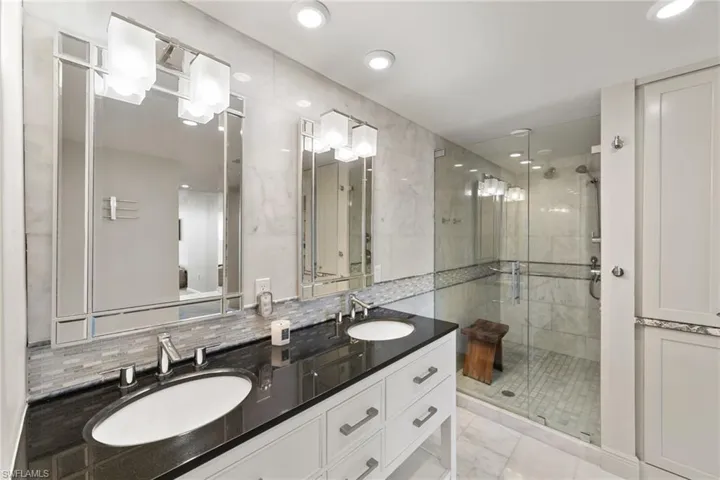 Full bath featuring a stall shower, double vanity, tasteful backsplash, and recessed lighting