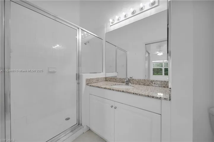 Full bathroom featuring a stall shower, vanity, and ceiling fan
