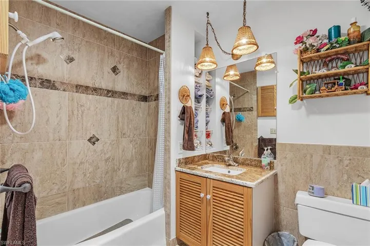 Full bathroom featuring vanity, shower / tub combo, toilet, and tile walls