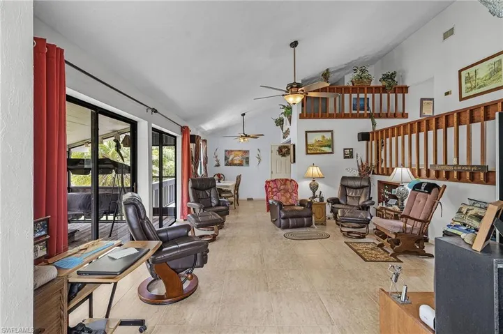 Living room with tile patterned floors, ceiling fan, and high vaulted ceiling