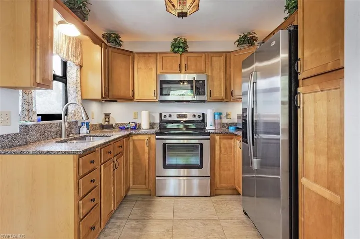 Kitchen featuring dark stone countertops, sink, appliances with stainless steel finishes, and light tile patterned floors