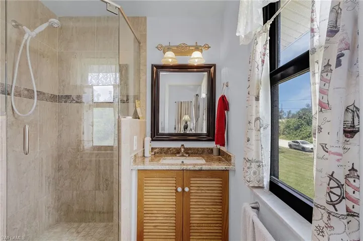 Bathroom with vanity, an enclosed shower, and a wealth of natural light