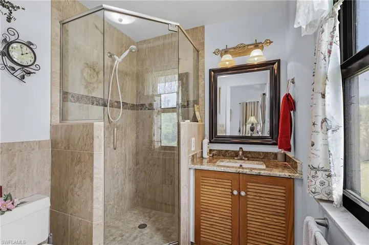 Bathroom featuring walk in shower, tile walls, toilet, and vanity