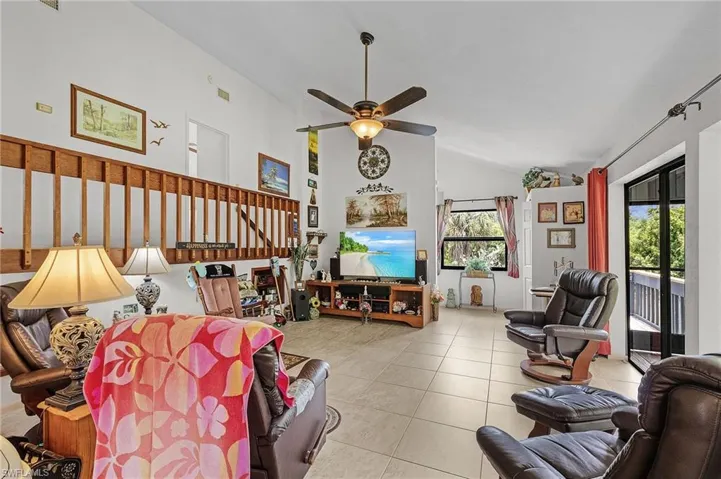 Tiled living room featuring lofted ceiling, ceiling fan, and plenty of natural light