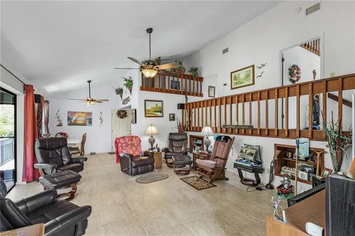 Tiled living room with high vaulted ceiling and ceiling fan