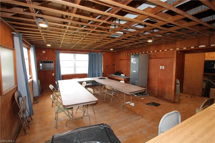 Dining area with a wall unit AC, wooden walls, and hardwood / wood-style floors