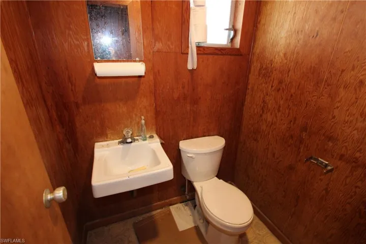Bathroom featuring tile floors, sink, wood walls, and toilet
