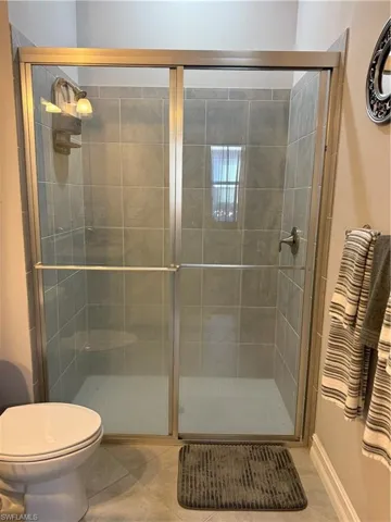 Bathroom featuring a shower stall and tile patterned flooring