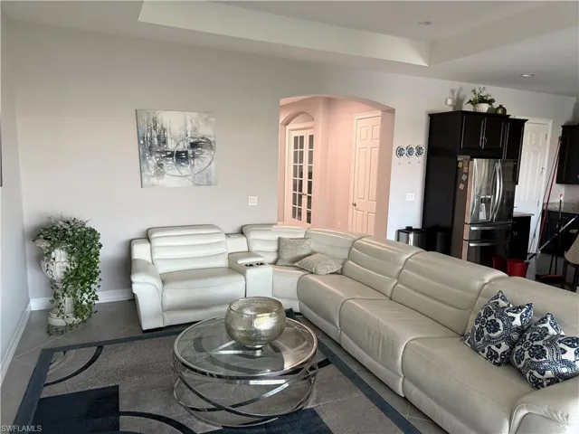 Tiled living area featuring arched walkways and baseboards