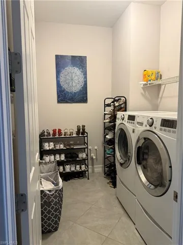 Laundry room with washer and clothes dryer and light tile patterned floors