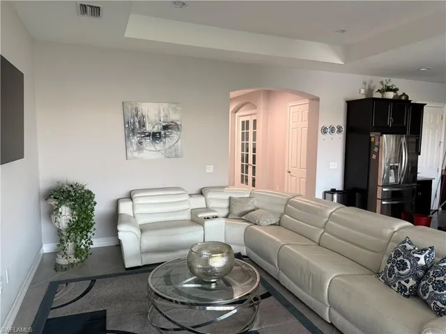 Tiled living area with arched walkways and a tray ceiling