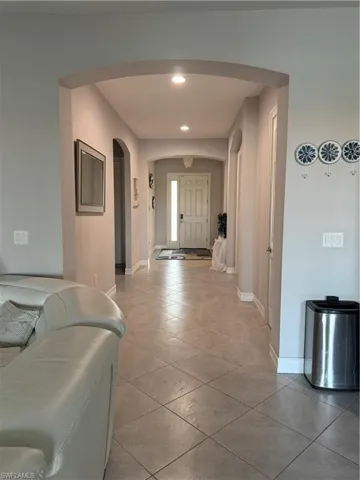 Corridor featuring recessed lighting, light tile patterned floors, and arched walkways