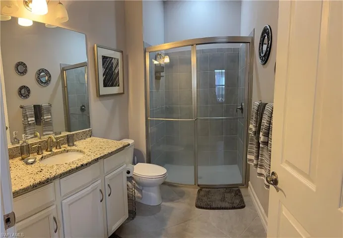 Bathroom with vanity, a shower stall, and light guest bathroom patterned