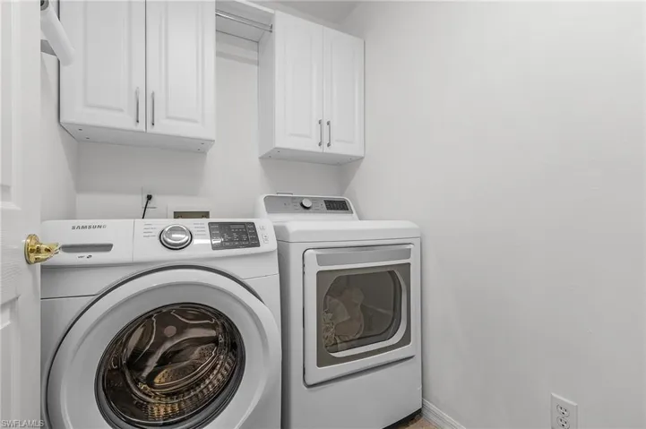 Washroom with cabinets and washing machine and clothes dryer
