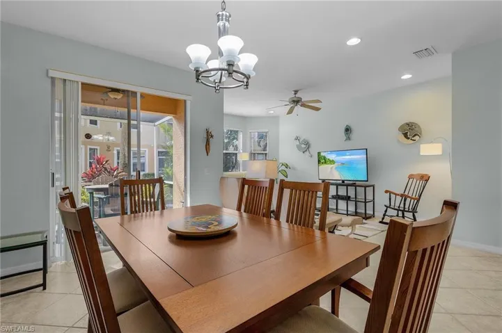 Tiled dining room with ceiling fan with notable chandelier