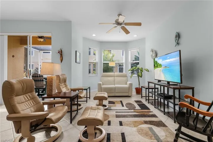 Living room with ceiling fan and light tile patterned flooring