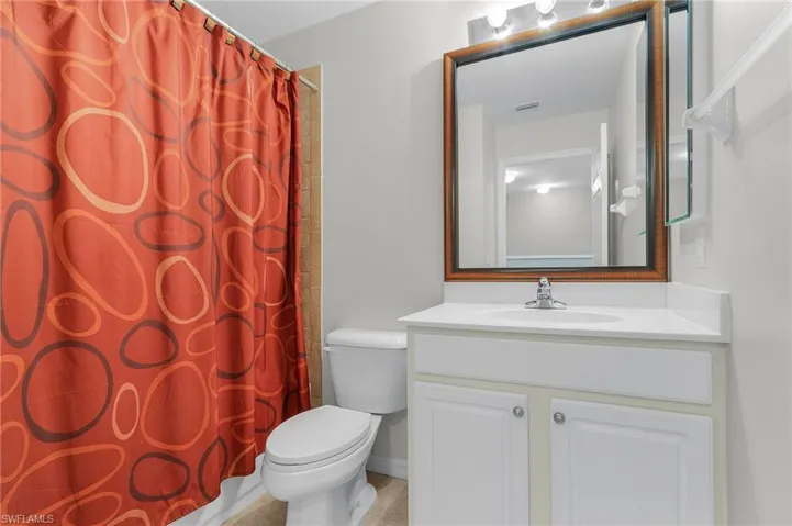Bathroom featuring a shower with curtain, vanity, and toilet
