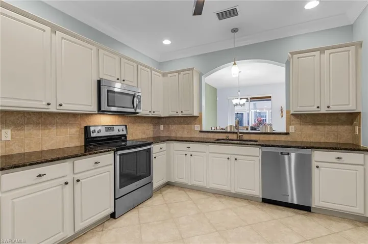 Kitchen featuring pendant lighting, appliances with stainless steel finishes, sink, and dark stone counters