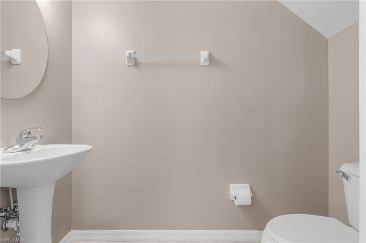 Bathroom with lofted ceiling, toilet, and sink