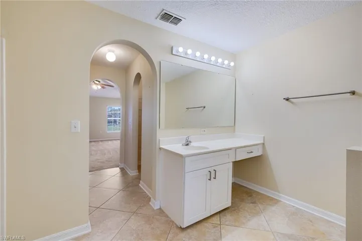 Full bath with vanity, ceiling fan, a textured ceiling, light tile patterned floors, and light carpet